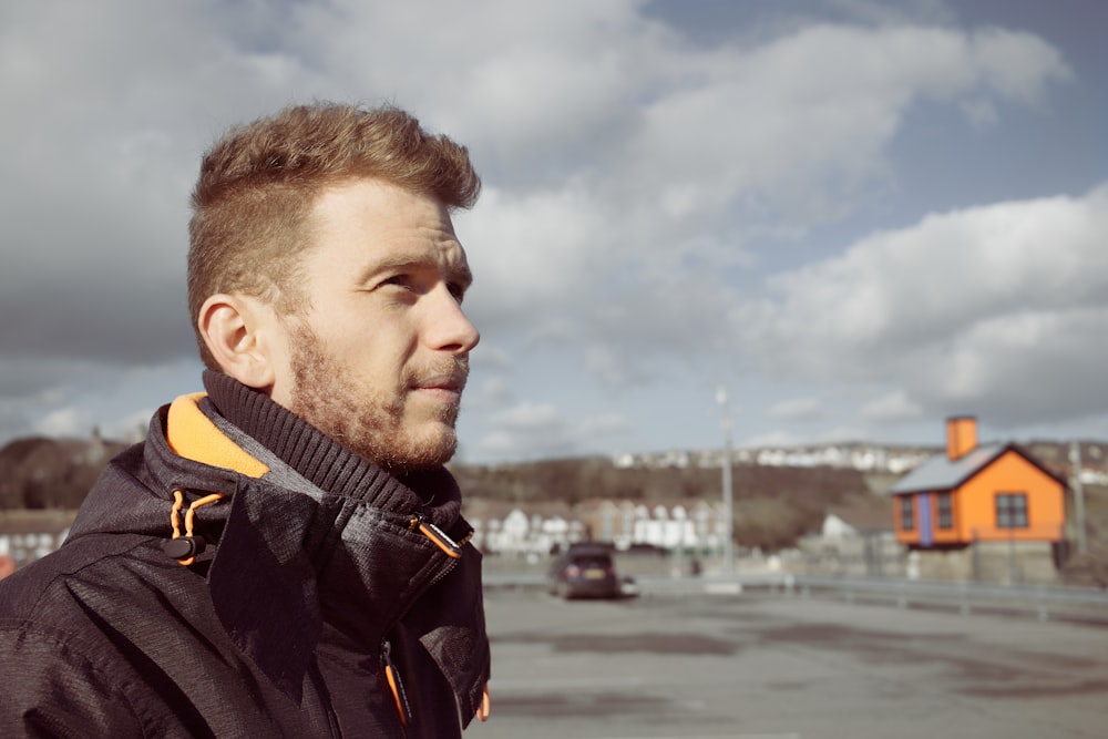 a man standing in a parking lot with a house in the background