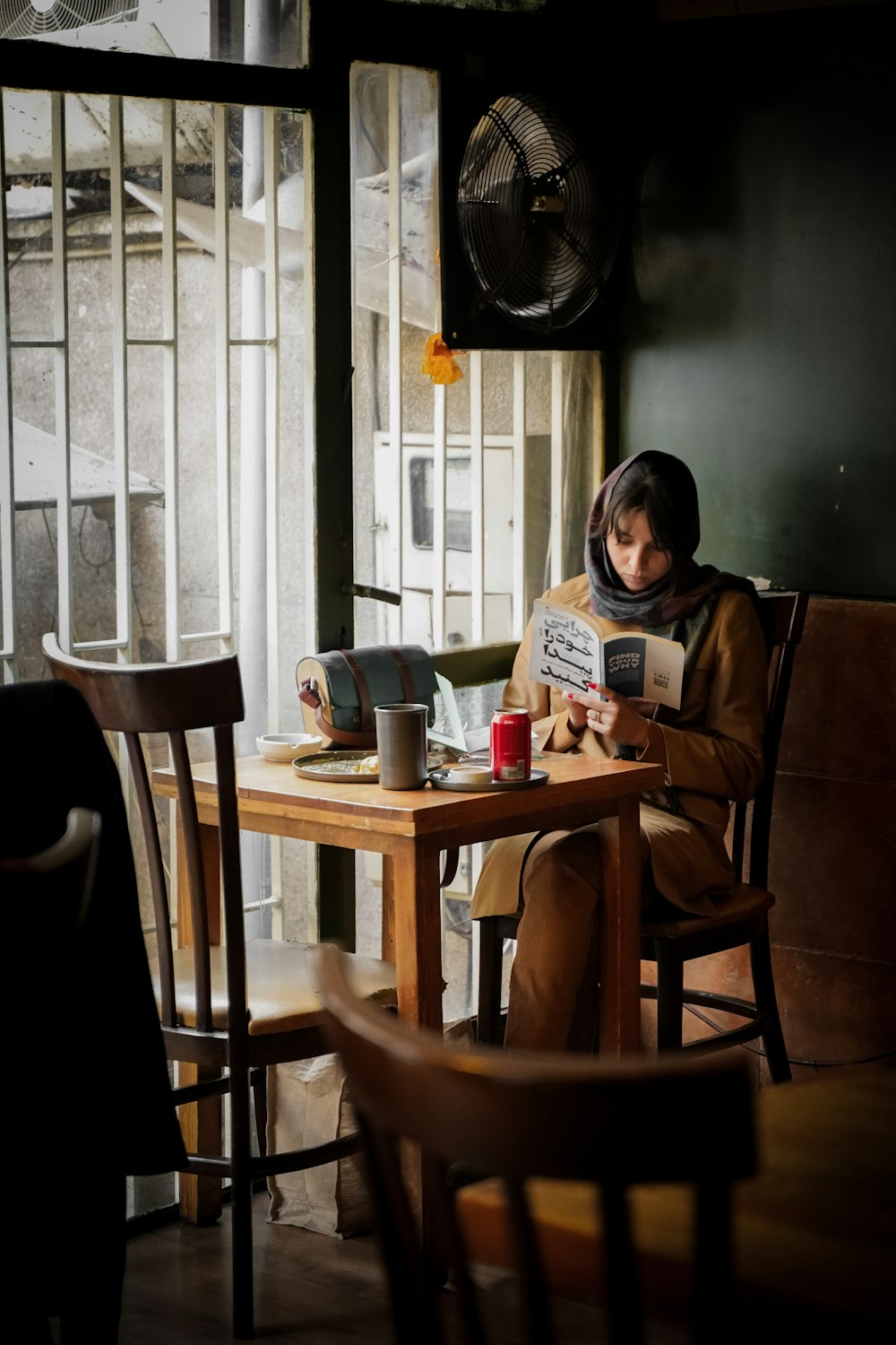 a woman sitting at a table reading a book