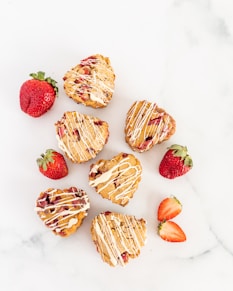 a marble table topped with heart shaped pastries and strawberries