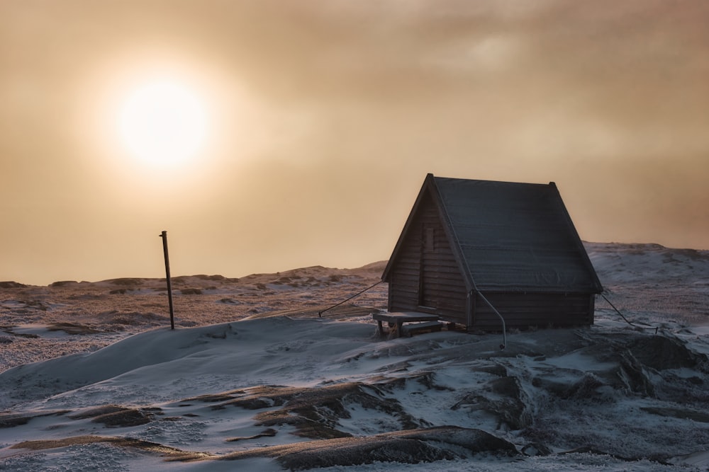 a small cabin sitting on top of a snow covered hill