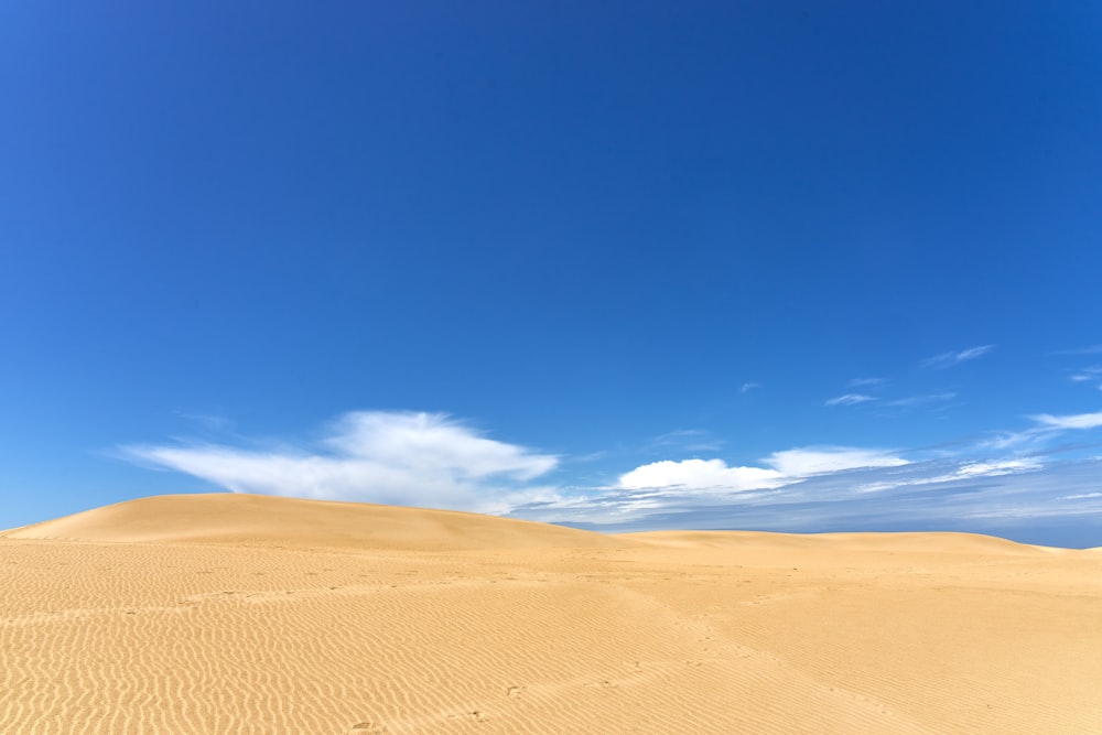 a large sand dune with a blue sky in the background