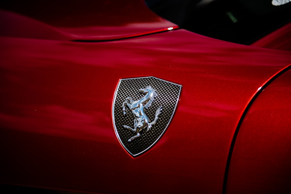 the emblem on the front of a red sports car