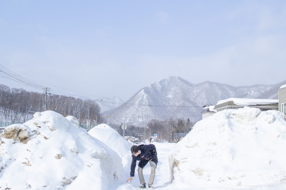 a man kneeling down in the snow next to a pile of snow