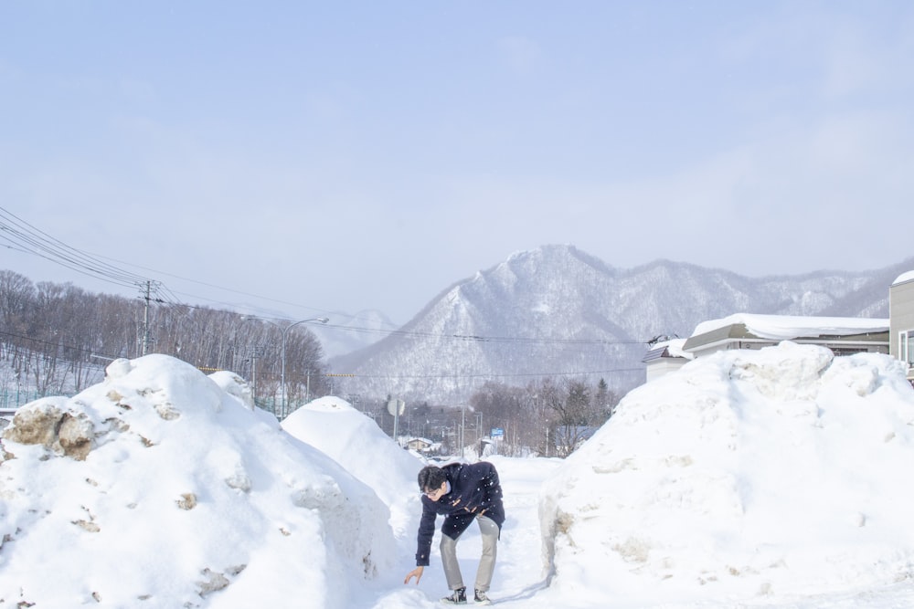 Un hombre arrodillado en la nieve junto a un montón de nieve