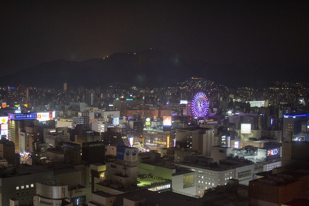 a city at night with a ferris wheel in the distance
