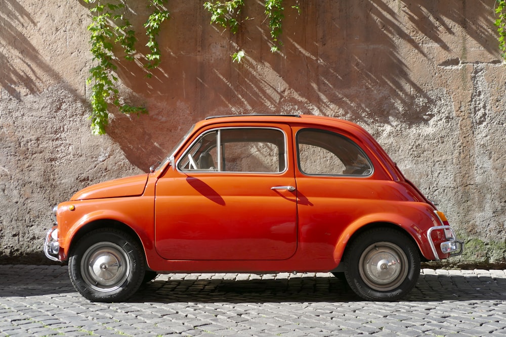 an orange car parked on a cobblestone street