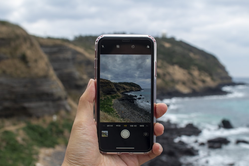 a person taking a picture of the ocean with a cell phone