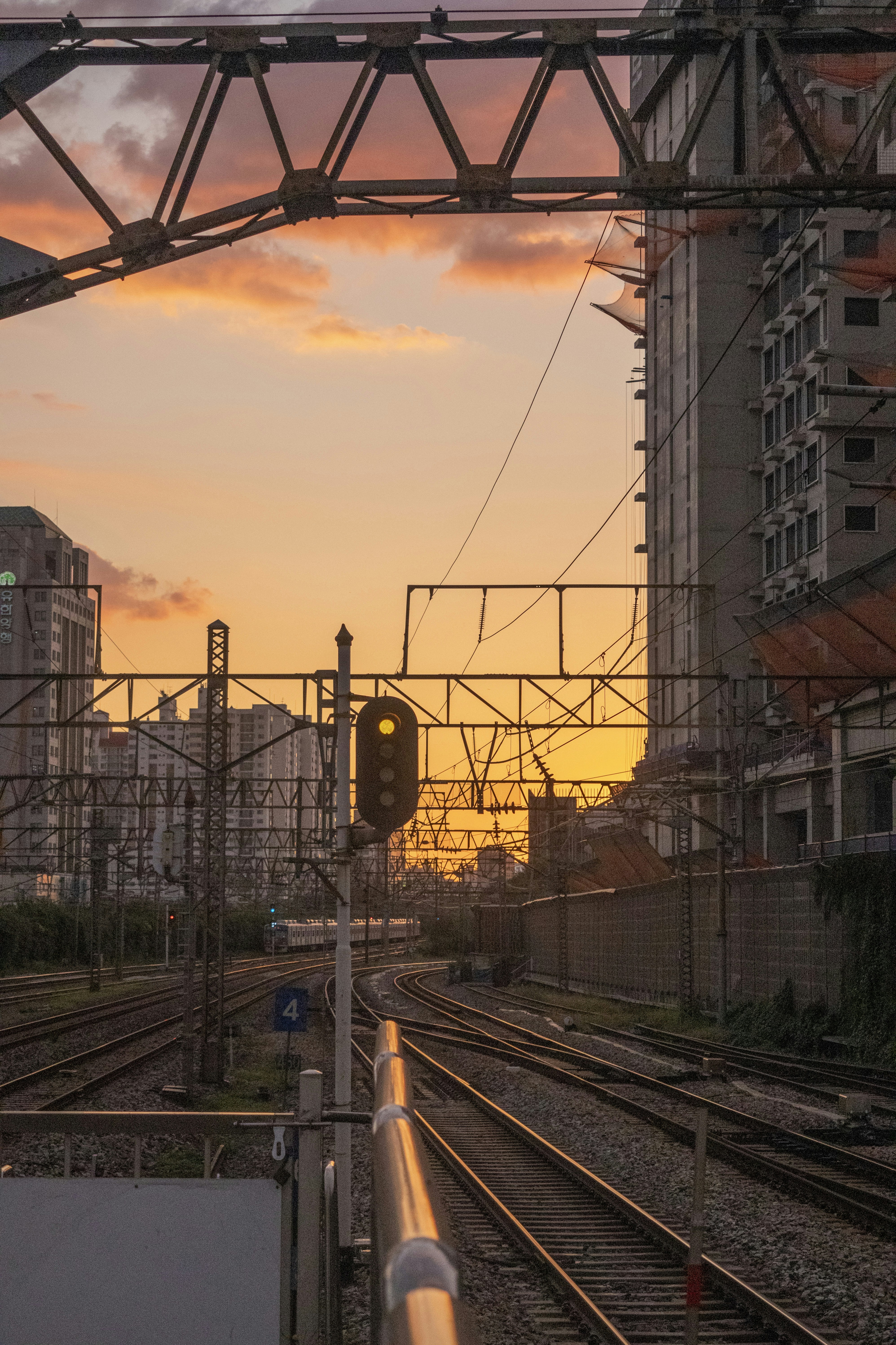 a train track with a stop light and buildings in the background