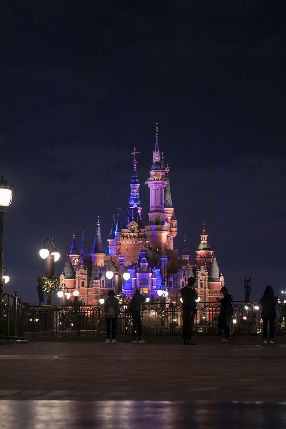 a castle lit up at night with people standing in front of it