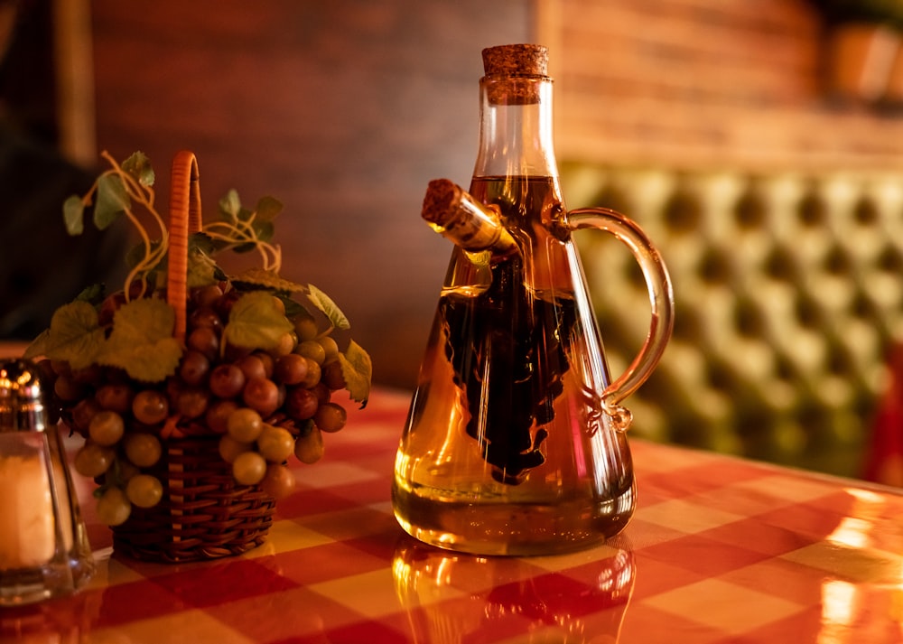 a bottle of wine sitting on top of a table next to a basket of grapes