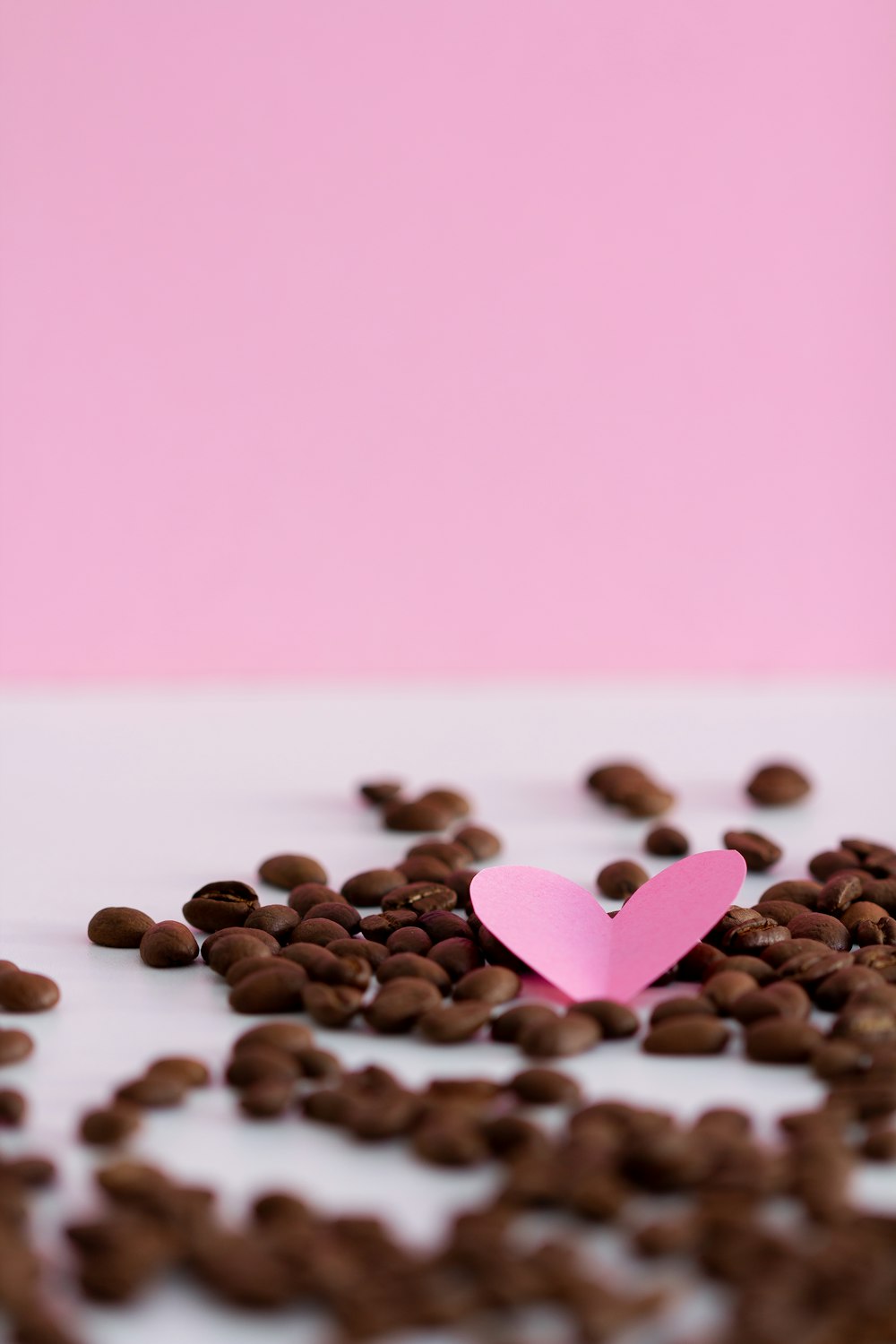 a pink paper heart surrounded by coffee beans