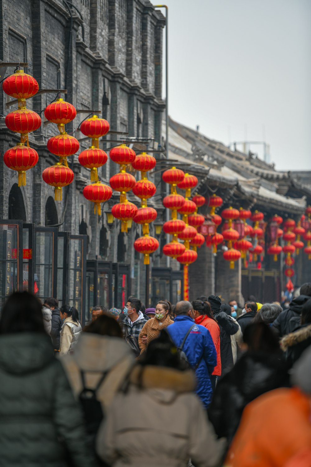 a group of people walking down a street under red lanterns