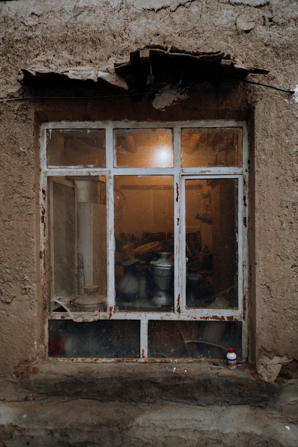 una ventana rota con ollas y sartenes en ella