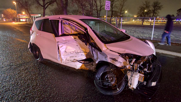 A damaged car on the side of a suburban Illinois road with emergency lights flashing.