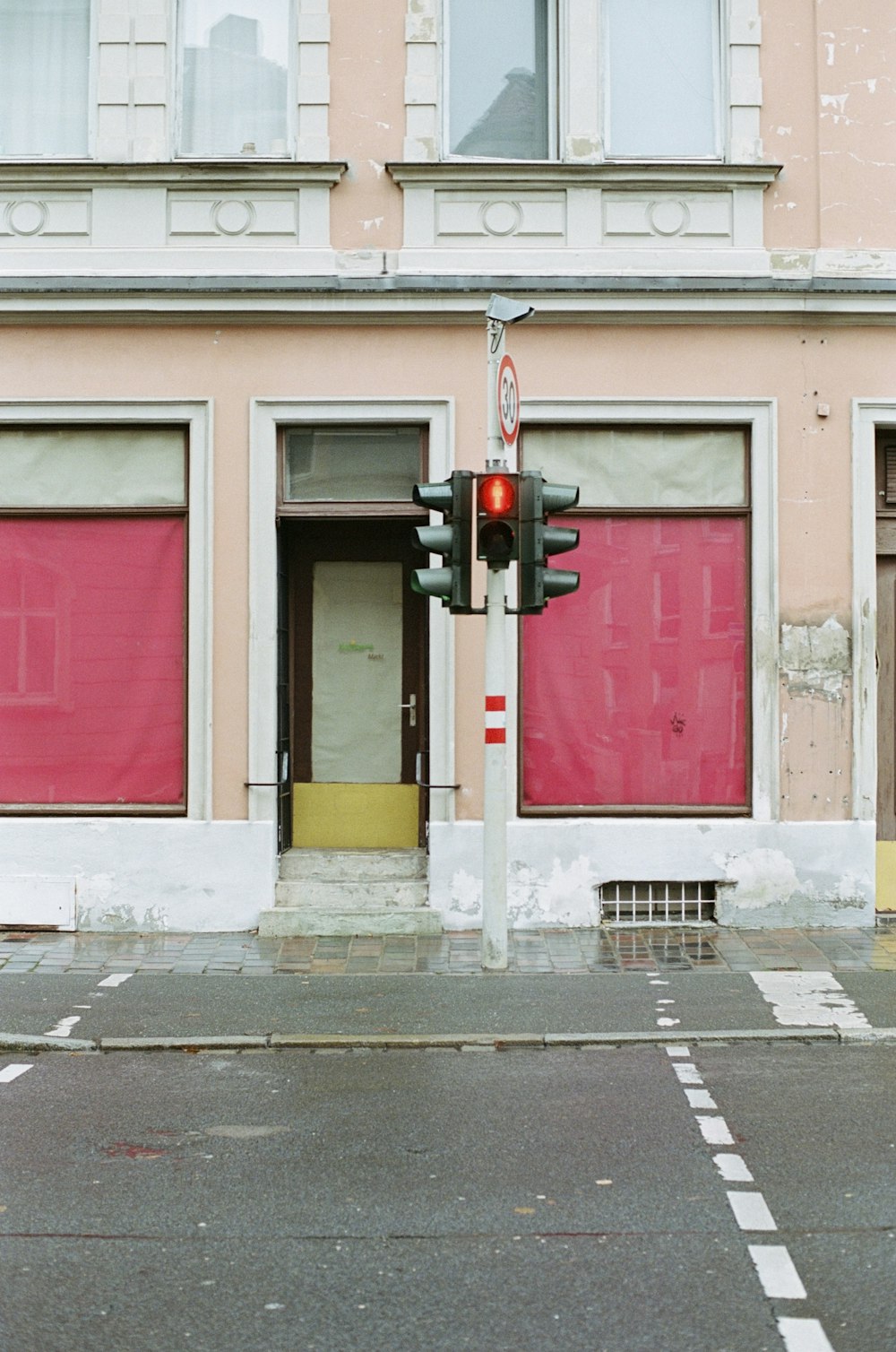 a red stop light sitting in front of a pink building