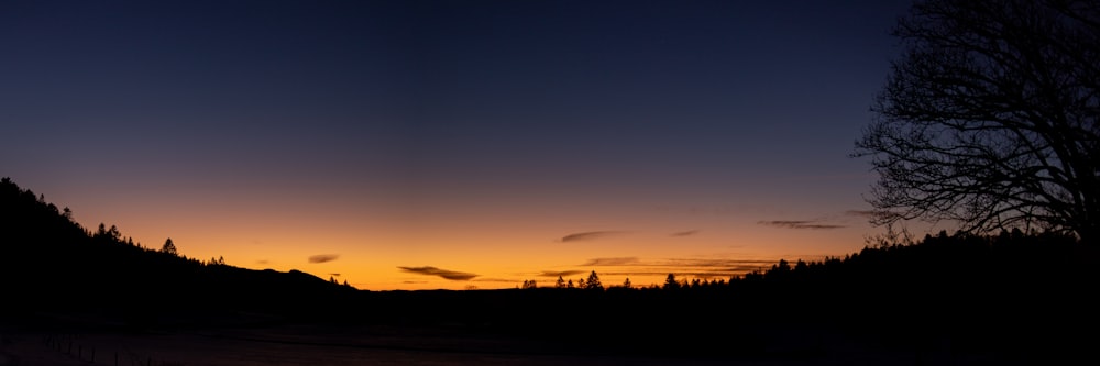 the sun is setting over the mountains and trees