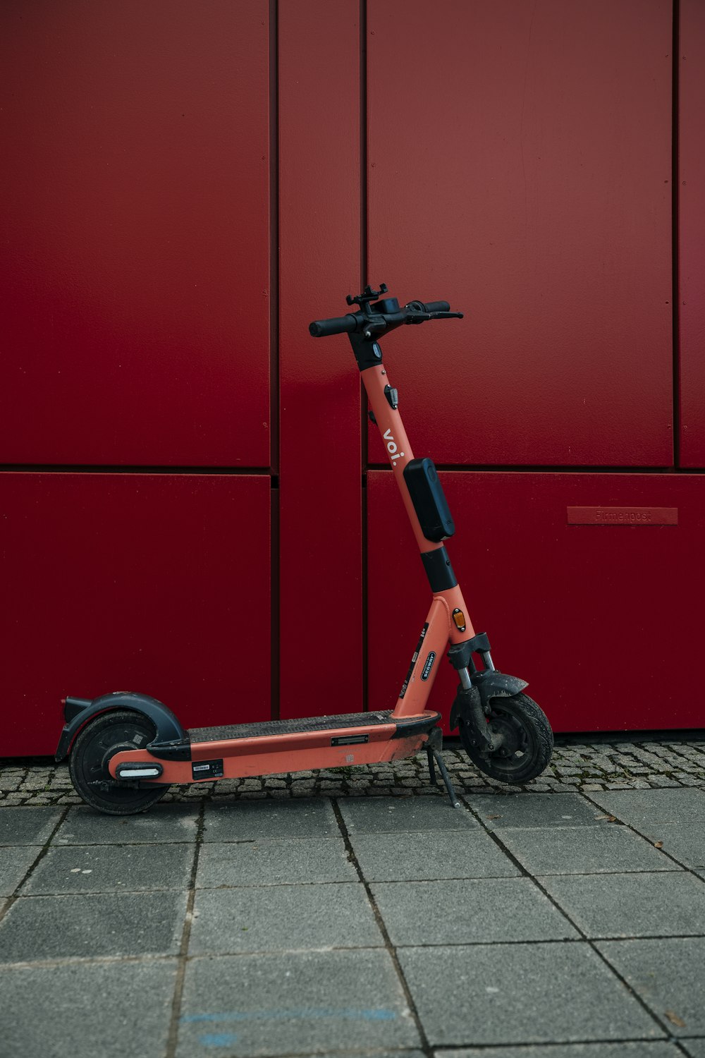 an orange scooter parked in front of a red wall