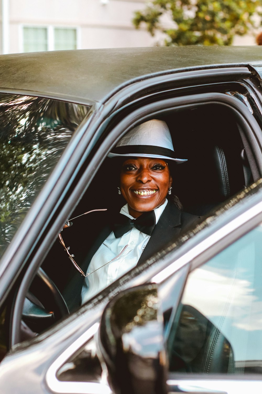 a woman in a car wearing a hat and a bow tie