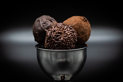 Hand holding a delicate truffle with a smooth chocolate coating