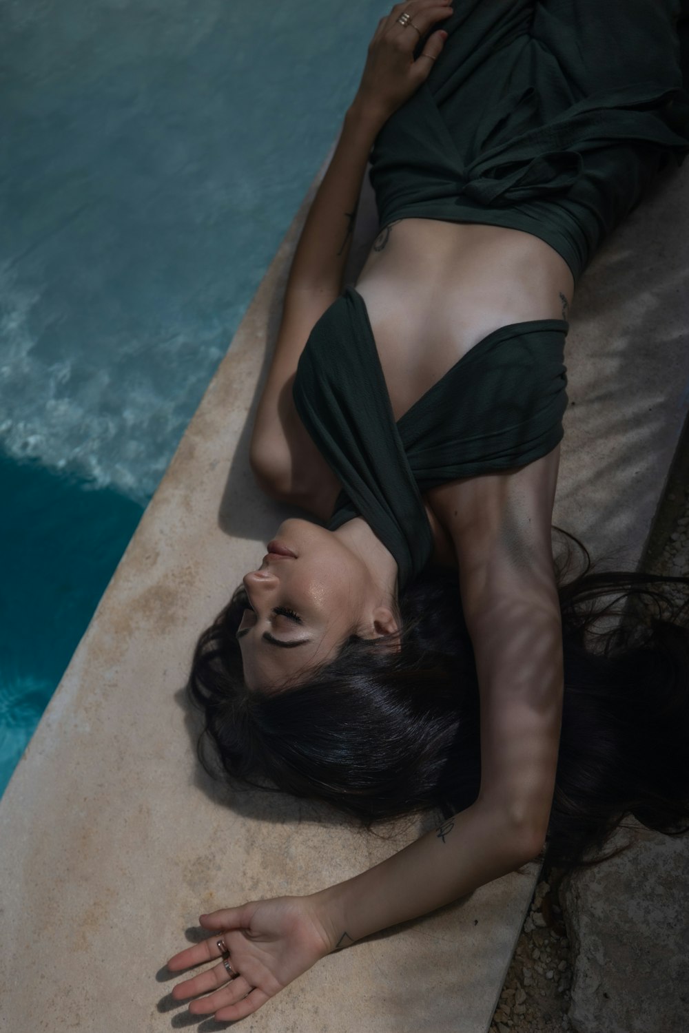 a woman laying on the ground next to a swimming pool
