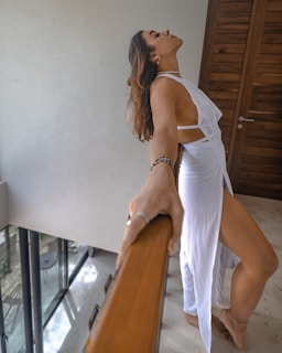a woman in a white dress leaning on a railing