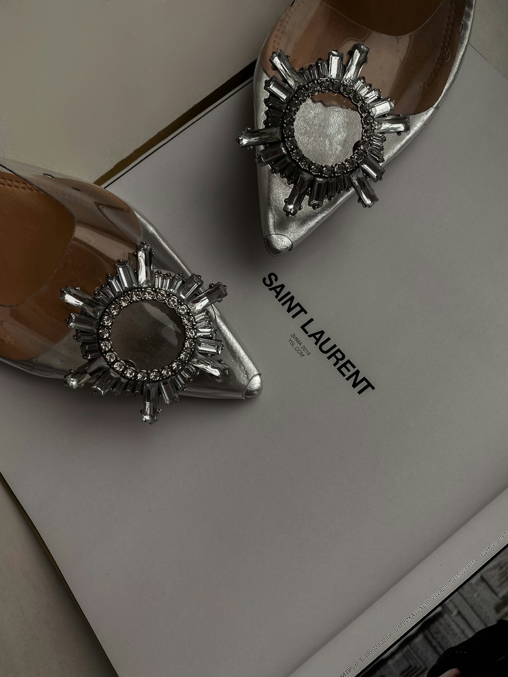 a pair of silver shoes sitting on top of a book