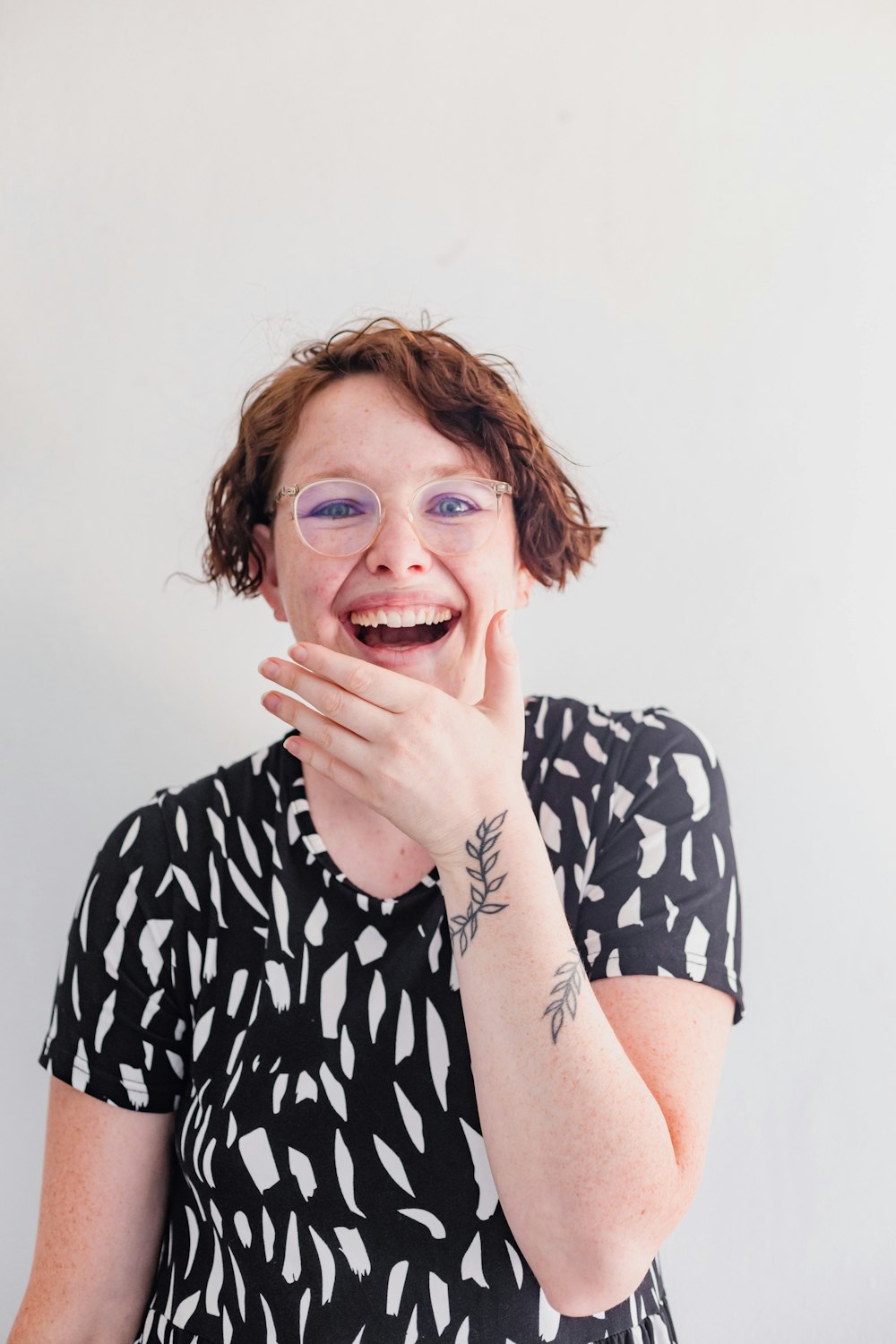 a woman smiling and covering her mouth with her hands