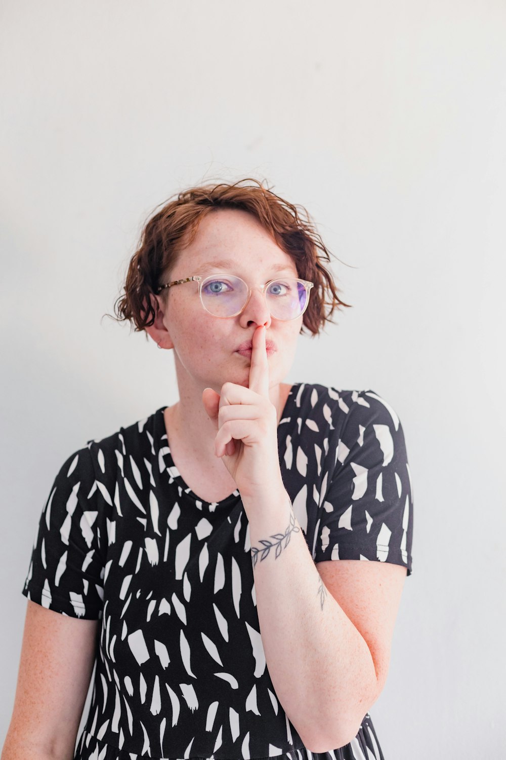 a woman in a black and white dress holding her finger to her lips