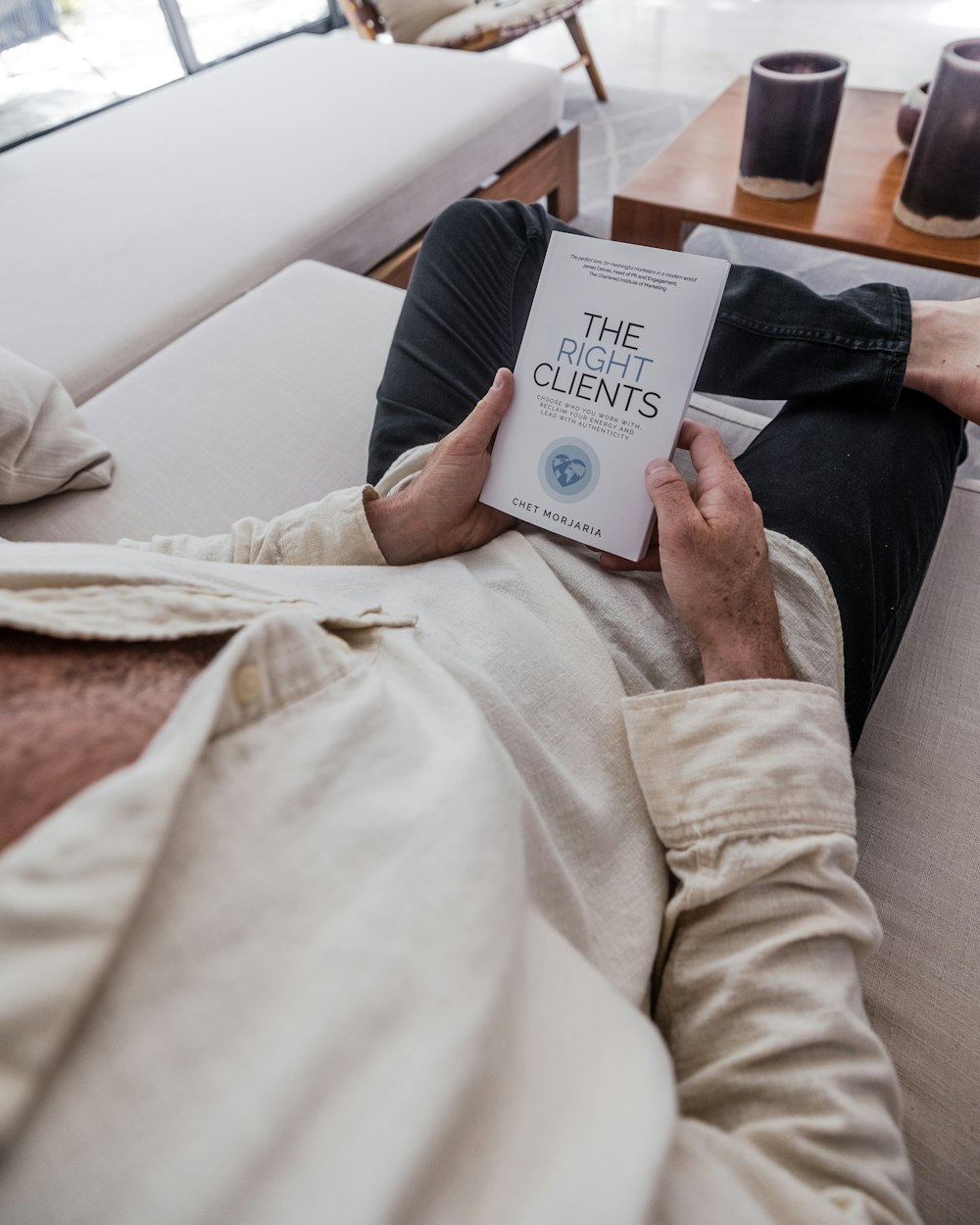 a man laying on a couch reading a book