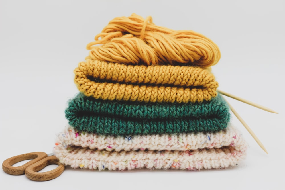 a stack of knitted sweaters and a pair of scissors