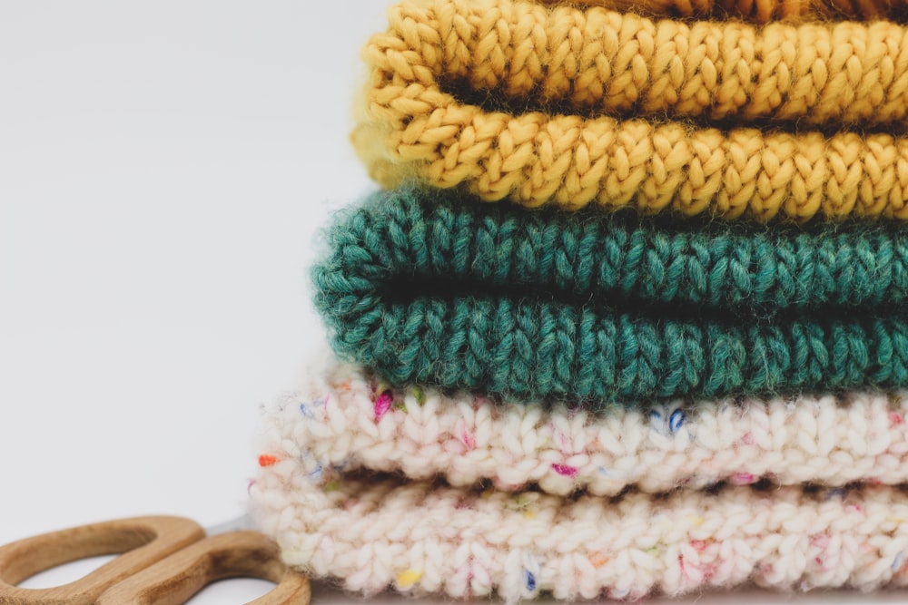 a stack of knitted sweaters and a pair of scissors
