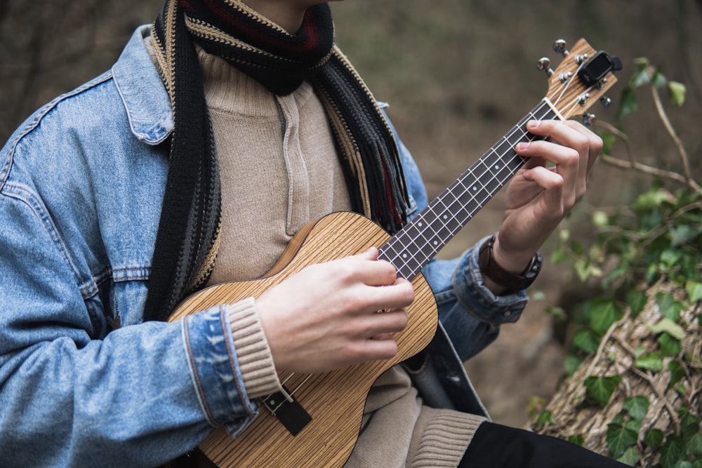 a man in a blue jacket is playing a ukulele