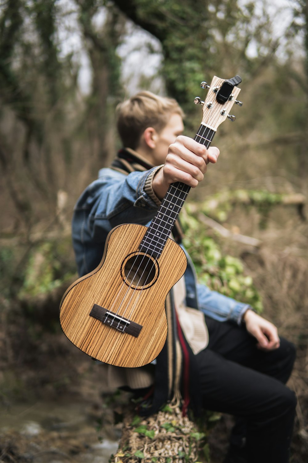 a man sitting on a rock holding a guitar