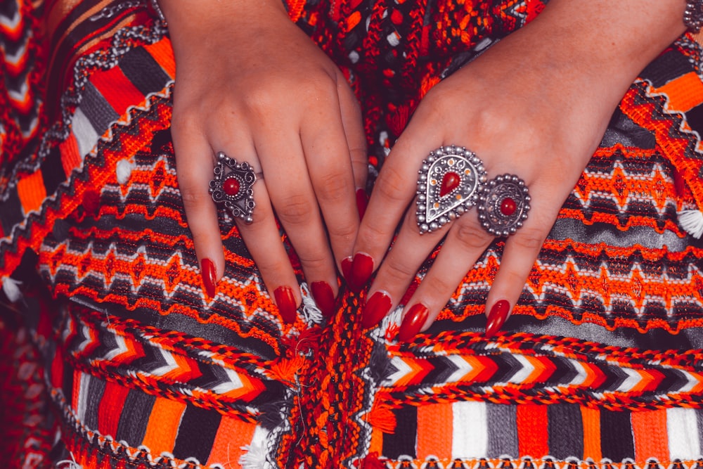 a close up of a person's hands with rings on their fingers