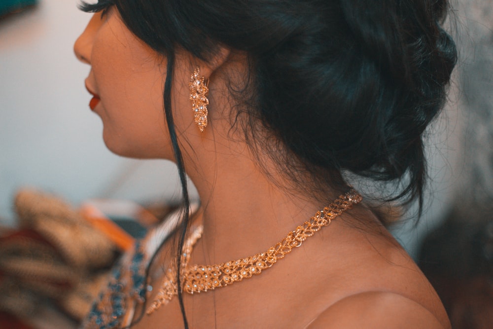 a woman wearing a gold necklace and earrings