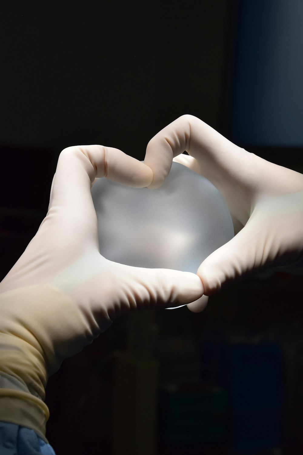 a person in white gloves holding a heart shaped object