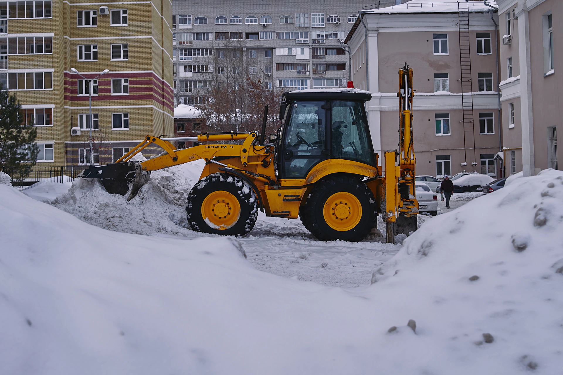 a bulldozer digging through the snow in a city