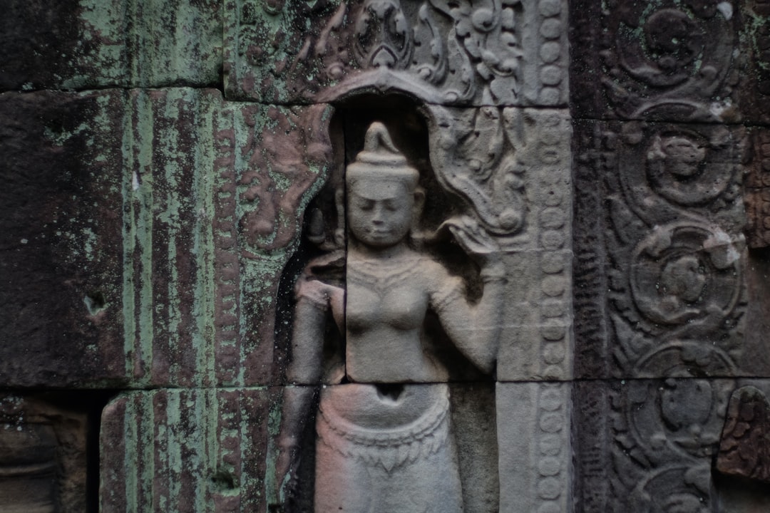 a statue of a woman standing next to a stone wall,