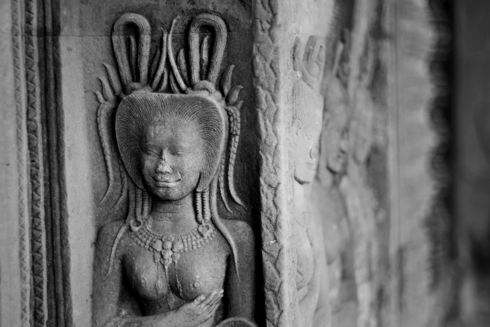 a black and white photo of a statue on a wall