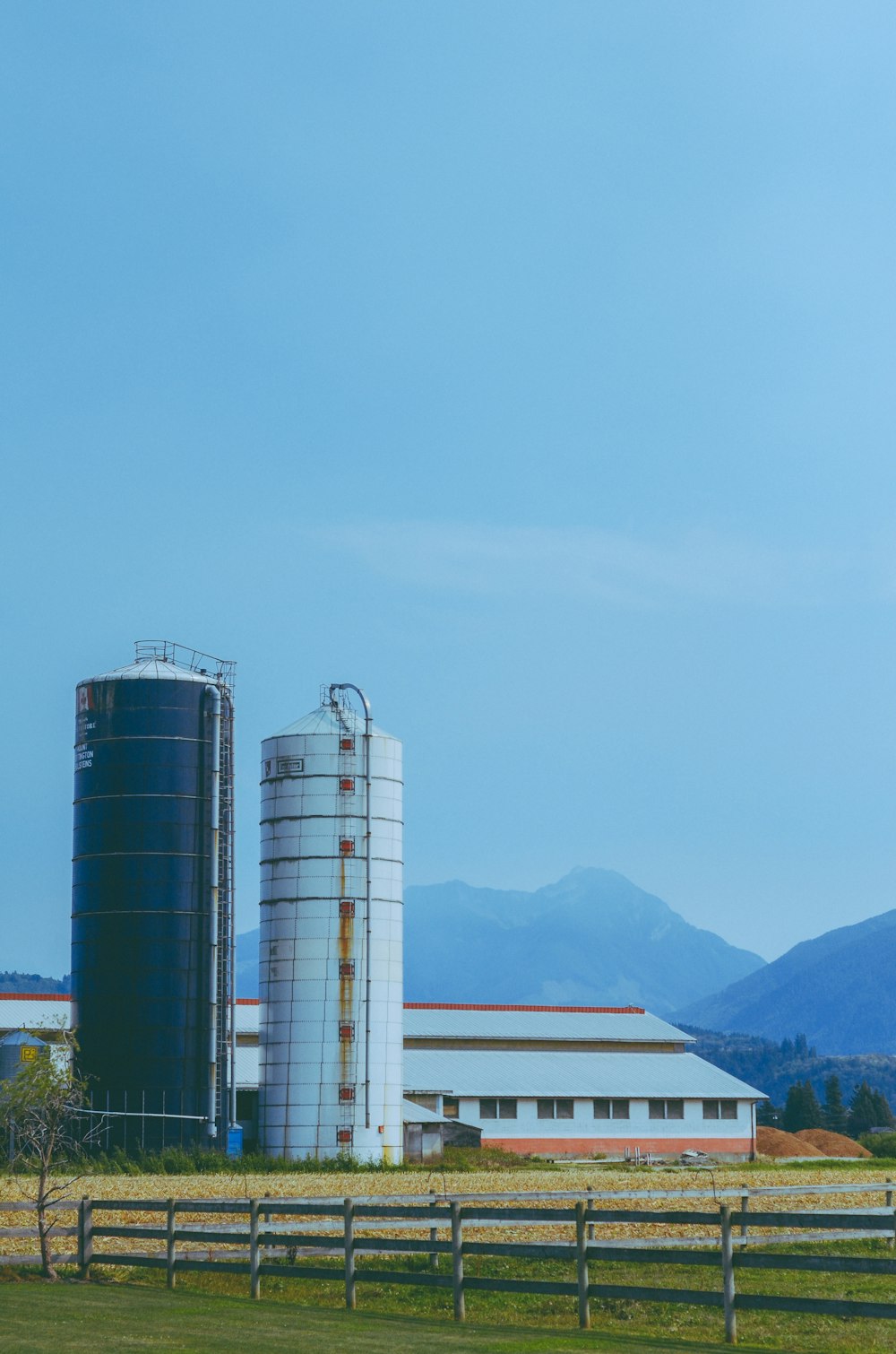 a farm with two silos and a barn in the background