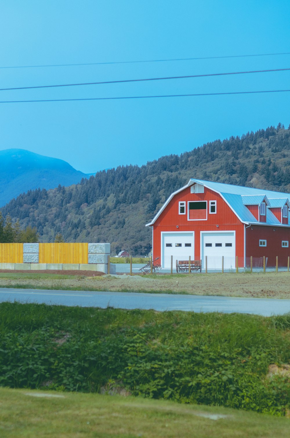 a red barn with a blue roof next to a road