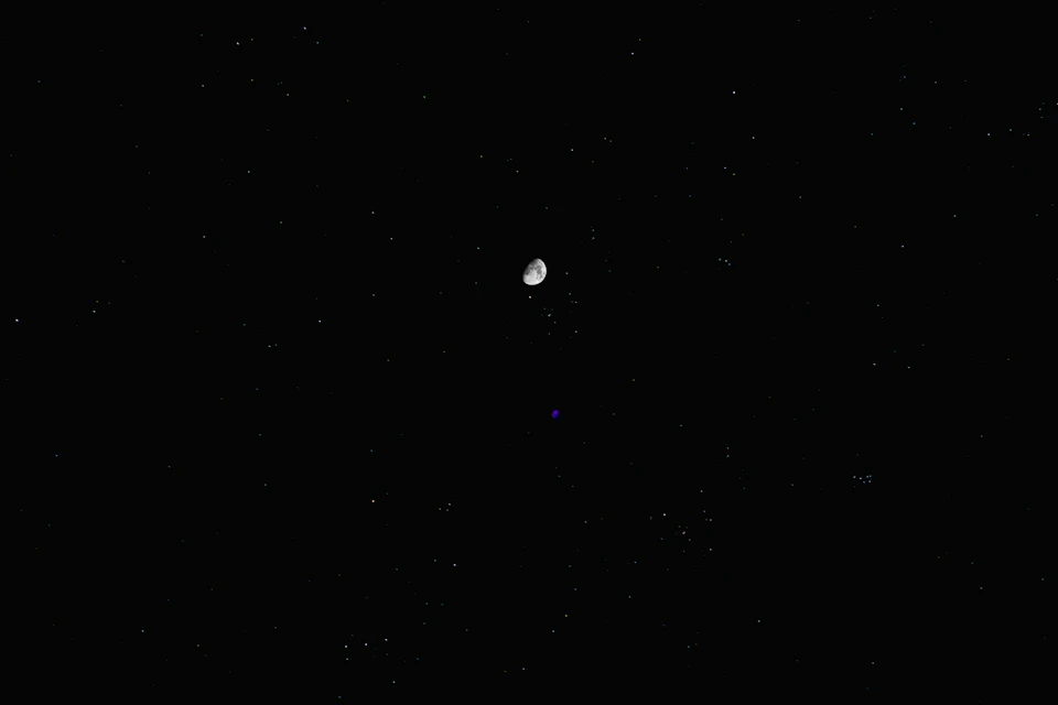 View of night sky with numerous stars and small white object in foreground