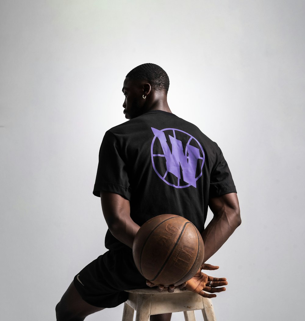 a man sitting on a stool holding a basketball