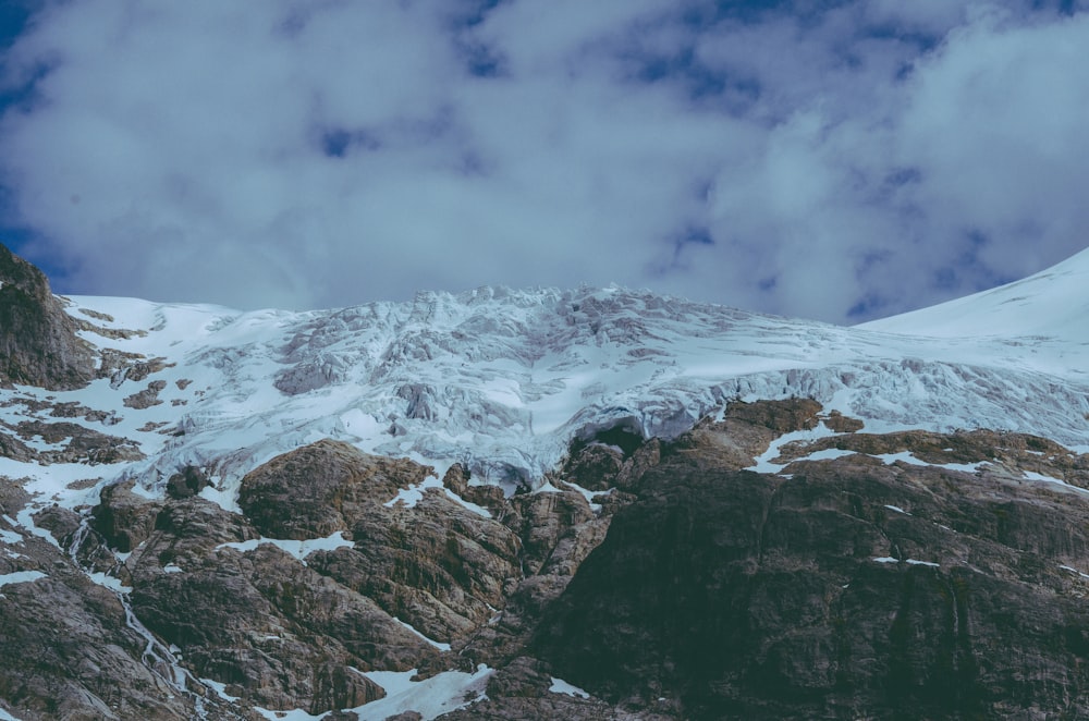 a mountain covered in snow under a cloudy sky