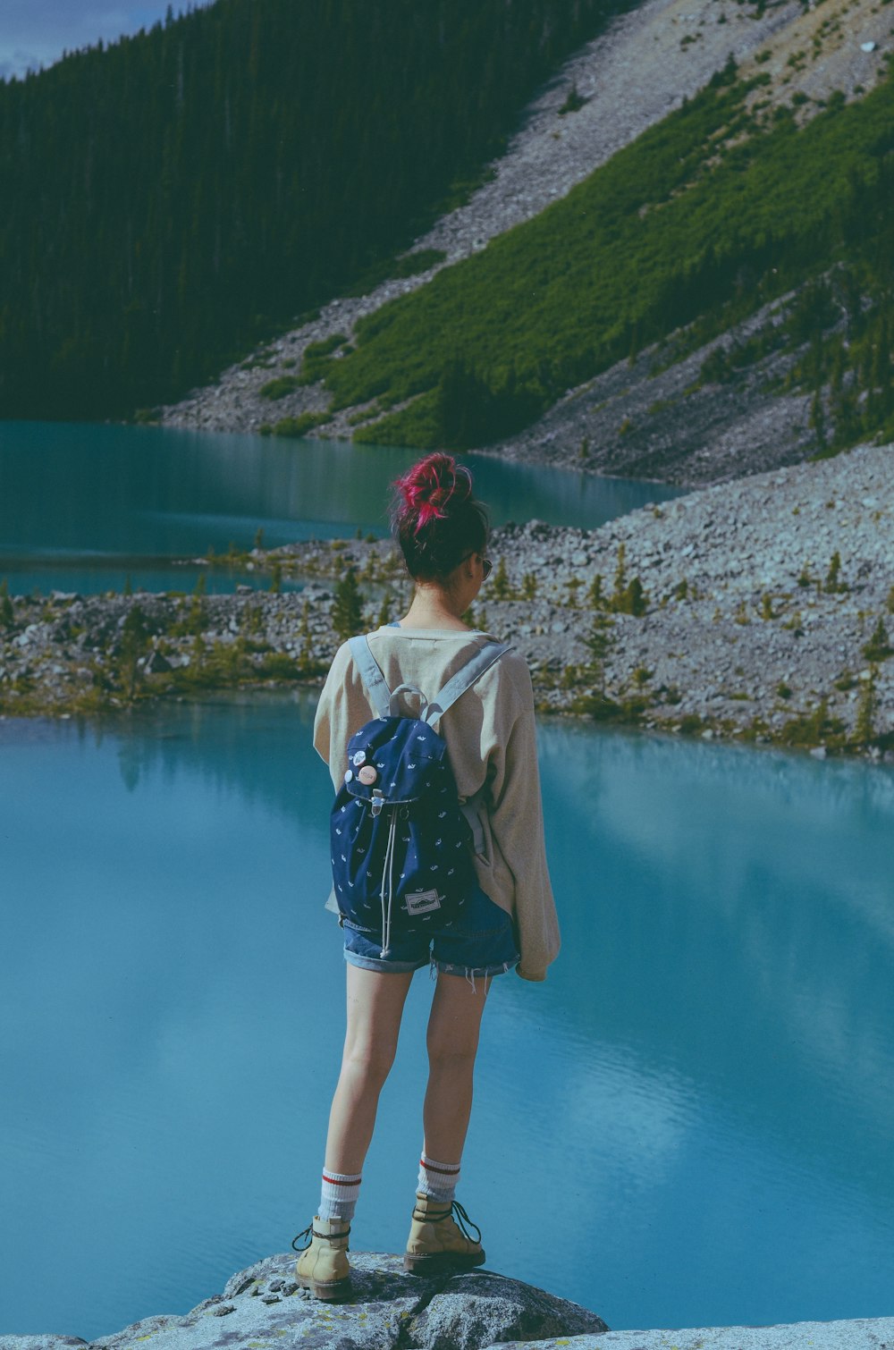 a person standing on a rock looking at a lake