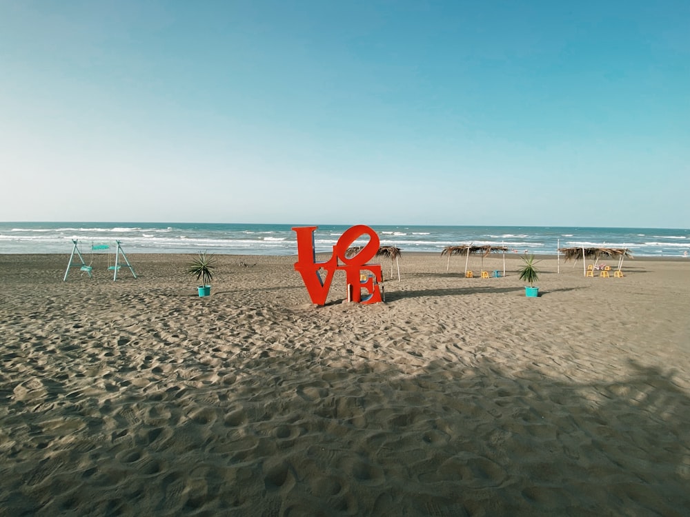 a large red love sign sitting on top of a sandy beach