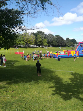A friendly group of children and adults playing laser tag in a lush forest setting.