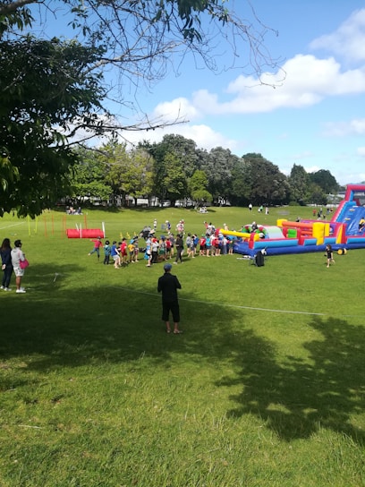 A group of friends laughing and bumping into each other inside colorful inflatable bubbles on a sunny field.
