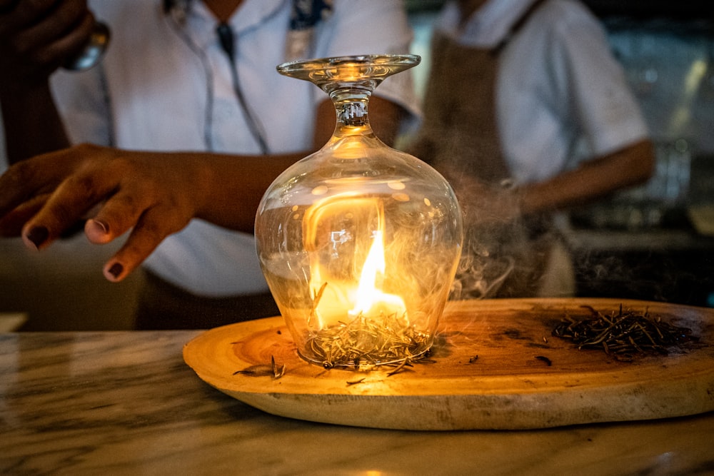 Una persona sentada en una mesa con una vela en una botella de vidrio