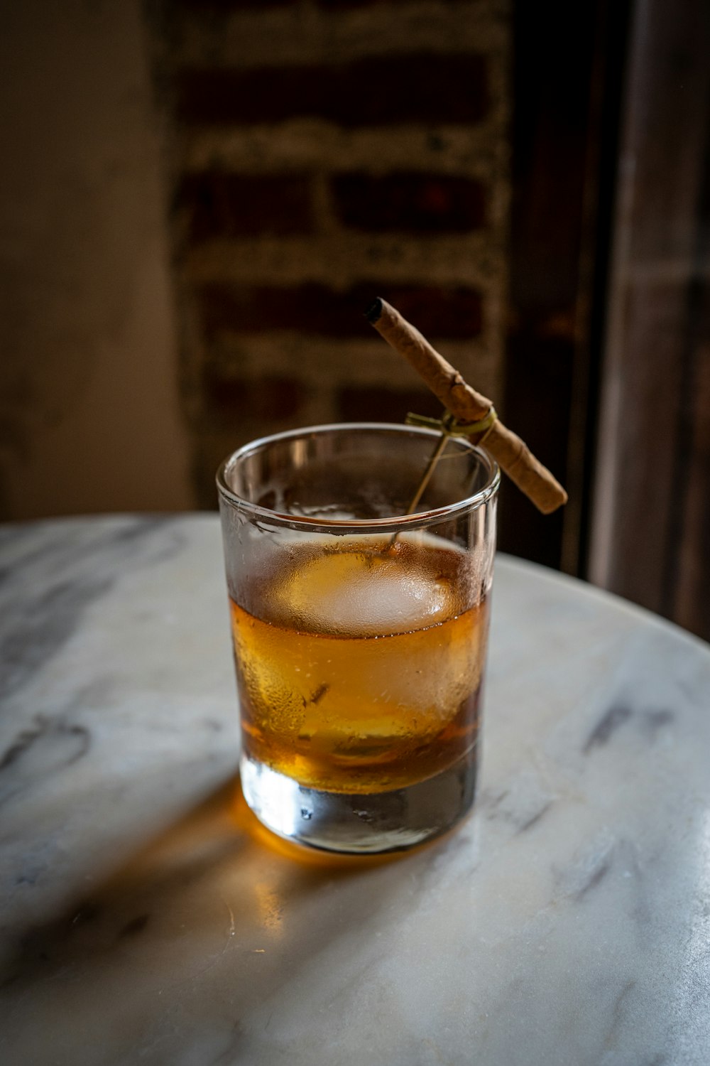 a glass of whiskey with a cinnamon stick sticking out of it